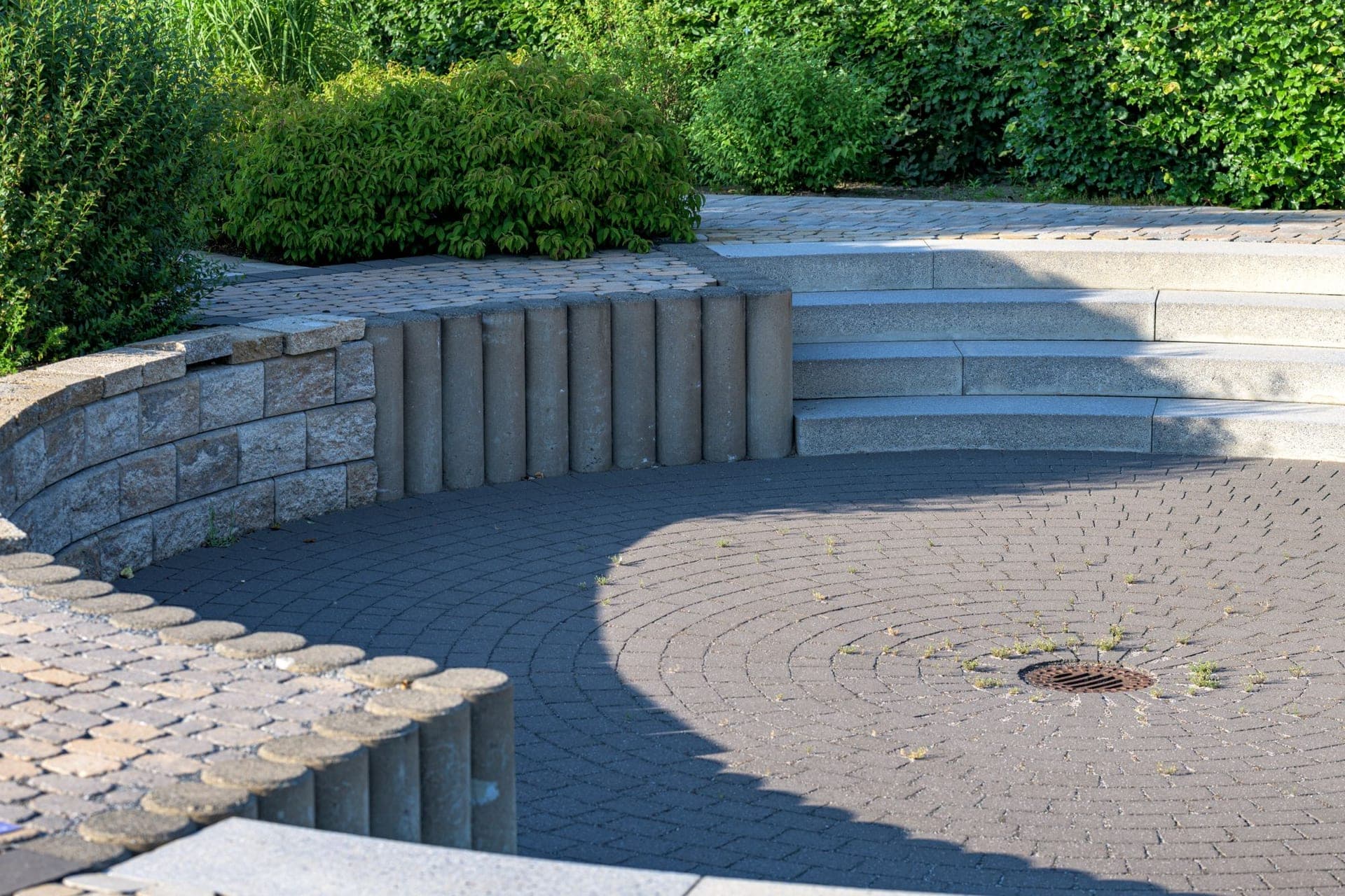 Circular paver patio with curved stone steps and retaining walls